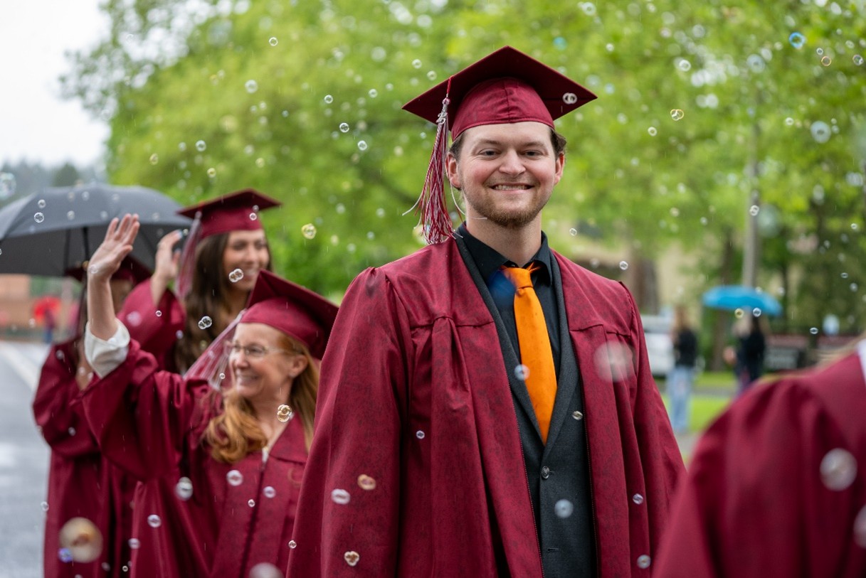 An NIC graduate smiles during the 2025 Commencement processional